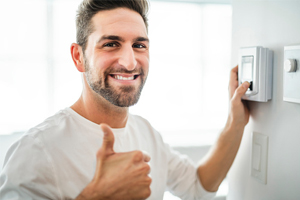 Man giving thumbs up while adjusting thermostat